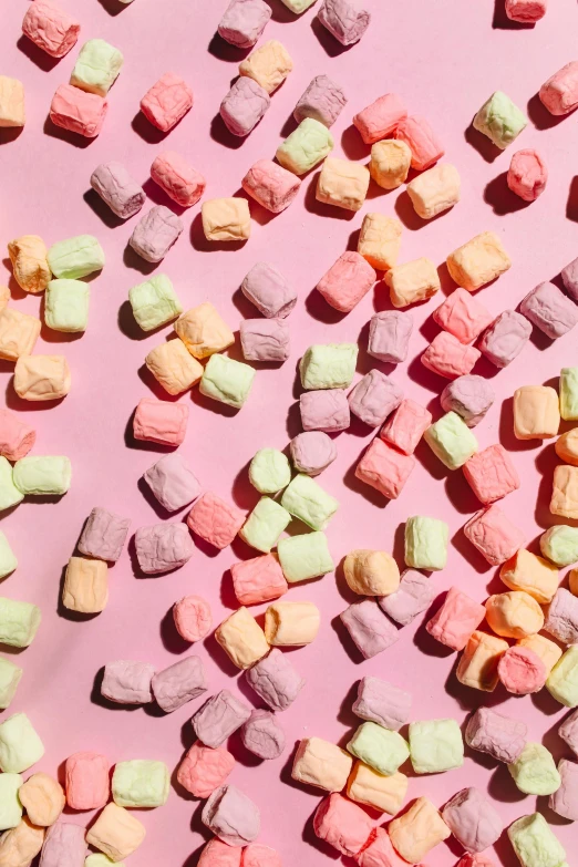 a pile of marshmallows sitting on top of a pink surface, gummy candies, subtle color variations, square shapes, promo image