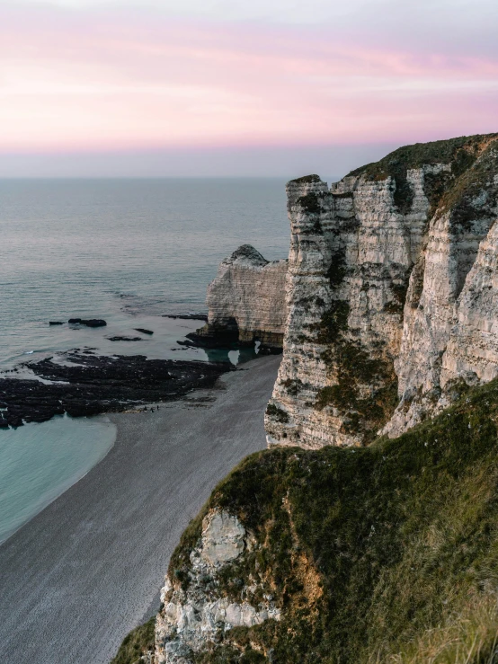 a group of people standing on top of a cliff next to the ocean, a matte painting, by Raphaël Collin, pexels contest winner, renaissance, normandy, cliff side at dusk, beach is between the two valleys, white stone arches