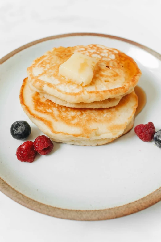 a stack of pancakes sitting on top of a white plate, a portrait, unsplash, berries, plain background, a pair of ribbed, butter