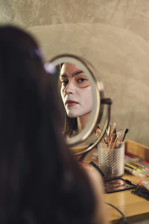 a woman getting her makeup done in front of a mirror, inspired by Elsa Bleda, trending on pexels, hyperrealism, wearing wooden mask, porcelain skin ”, androgynous person, studio photo