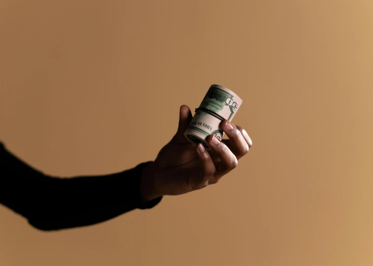 a person holding a stack of money in their hand, unsplash, visual art, cinestill hasselblad 8 5 mm, light tan, ad image, offering the viewer a pill