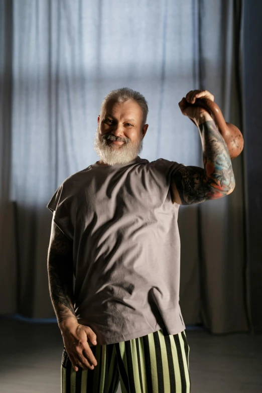 a man standing in front of a window with his arm in the air, a tattoo, inspired by Samuel Silva, some grey hair in beard, rodney matthew, wearing a tee shirt and combats, prosthetic arm