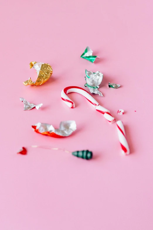 a pile of candy canes sitting on top of a pink surface, by Peter Alexander Hay, pexels, broken toys are scattered around, close up of single sugar crystal, with lots of thin ornaments, profile image