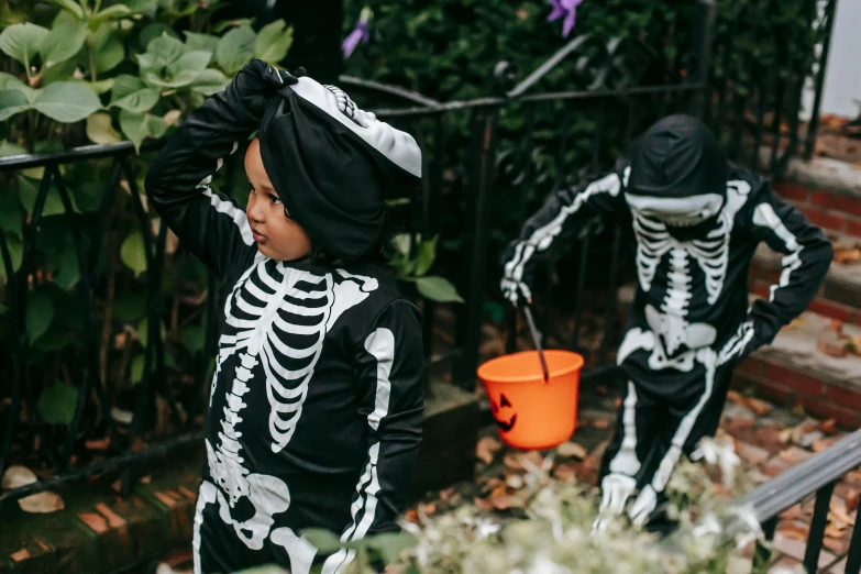 two little boys dressed up in skeleton costumes, a cartoon, by Helen Stevenson, pexels contest winner, black, lifestyle, gardening, shot on sony a 7
