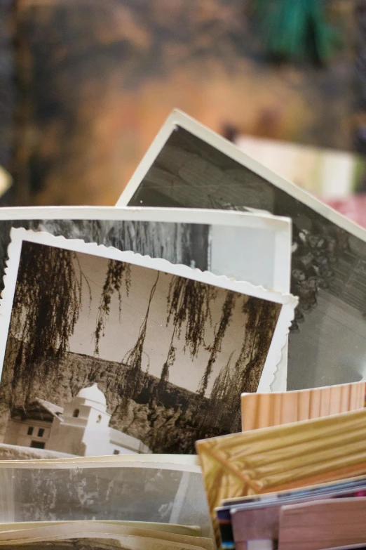 a pile of old photos sitting on top of a table, unsplash, beautiful surroundings, brown, photograph ”