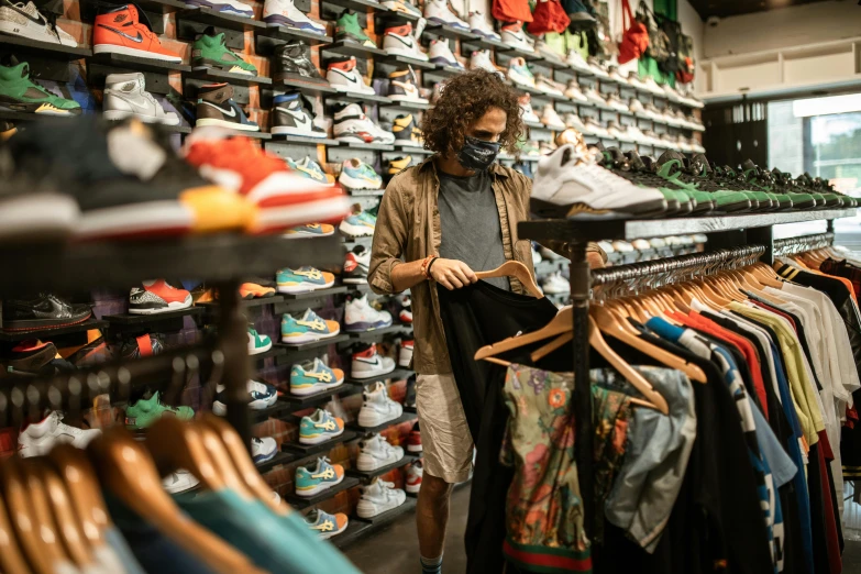 a man standing in front of a rack of shoes, wearing facemask and sunglasses, bay area, customers, sports