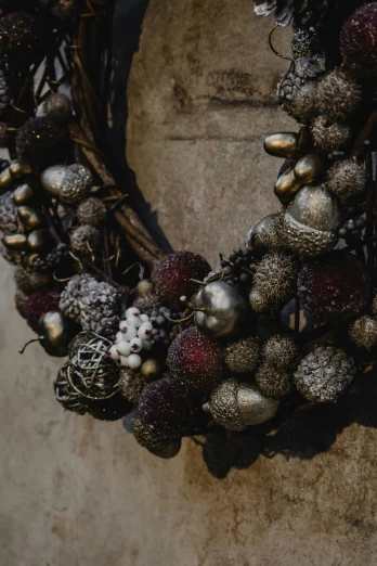 a close up of a wreath on a wall, inspired by Károly Markó the Elder, unsplash, baroque, maroon metallic accents, spheres, necklace on display, natural textures