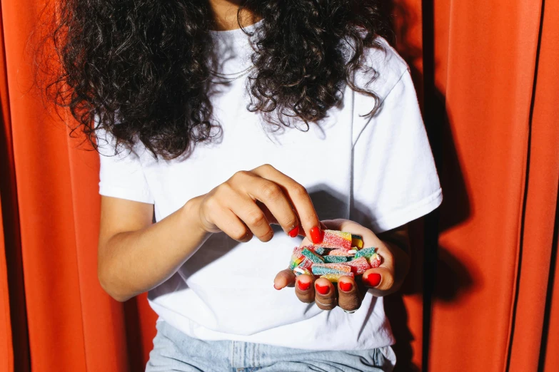 a close up of a person holding a candy, pills, female streetwear blogger, complaints, multi colour