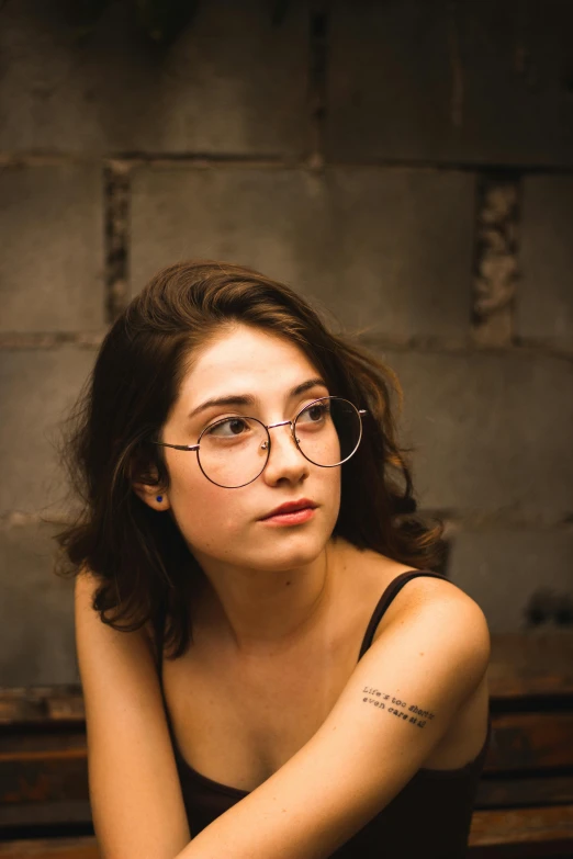 a woman with glasses sitting on a bench, an album cover, inspired by Elsa Bleda, trending on pexels, photorealism, handsome girl, headshot, indoor shot, small square glasses