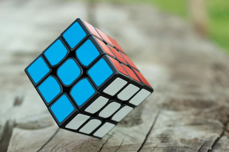 a rubik cube sitting on top of a wooden table, inspired by Ernő Rubik, unsplash, square, blender, islamic, knee