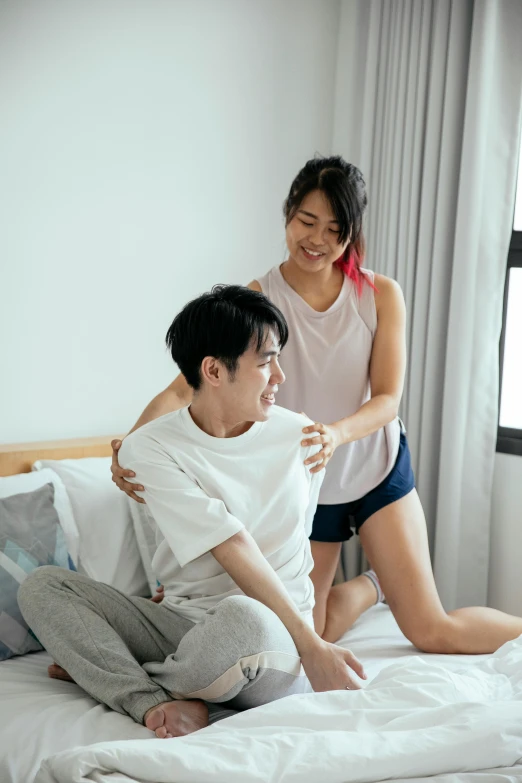 a man sitting on top of a bed next to a woman, inspired by Joong Keun Lee, pexels contest winner, happening, earing a shirt laughing, showing her shoulder from back, boy and girl, supportive