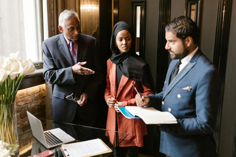 a group of people standing around a table, by Arabella Rankin, pexels contest winner, hurufiyya, standing at the resolute desk, business meeting, imaan hammam, promotional image