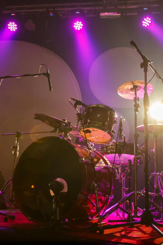 a group of drums sitting on top of a stage, sitting in front of a microphone, spherical, stingray, instrument