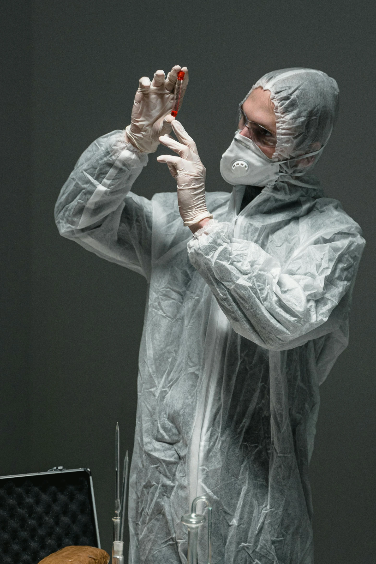 a man in a protective suit taking a picture with his cell phone, an album cover, pexels contest winner, plasticien, medical laboratory, grey robe, studio photo, holding syringe