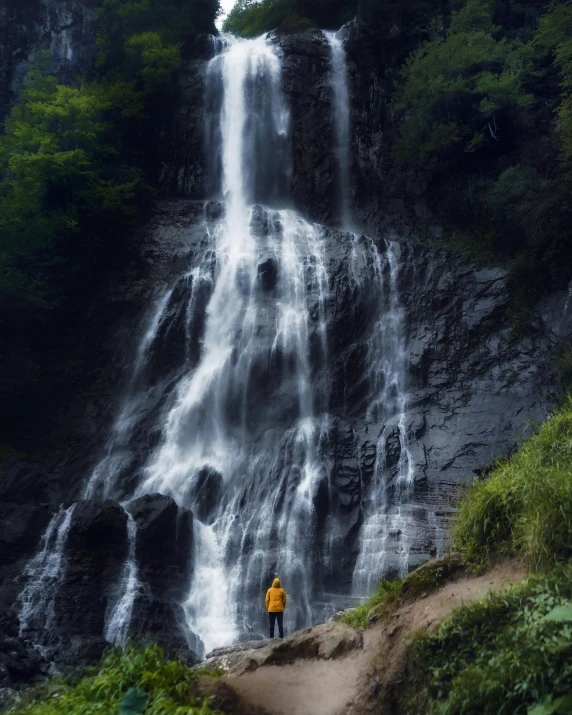 a person standing in front of a waterfall, from the distance