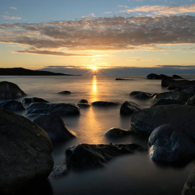 a sunset over a body of water with rocks in the foreground, by Olaf Gulbransson, pexels contest winner, grey, cloudless-crear-sky, fan favorite, minna sundberg