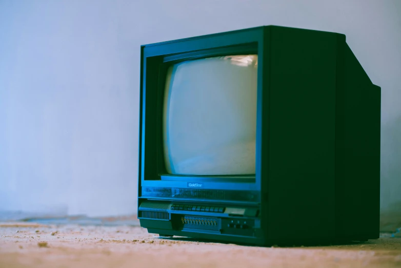 a small television sitting on top of a wooden floor, a cartoon, unsplash, bad vhs, crt tubes, politics, blue
