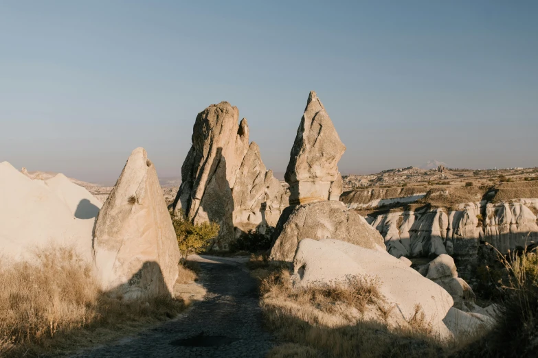 a man riding a skateboard on top of a dirt road, a marble sculpture, by Alexander Runciman, trending on pexels, tall stone spires, turkey, ((rocks)), natural morning light