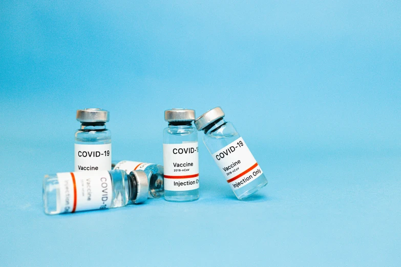 a couple of vials sitting next to each other on a blue surface, medical labels, thumbnail, covid, grey