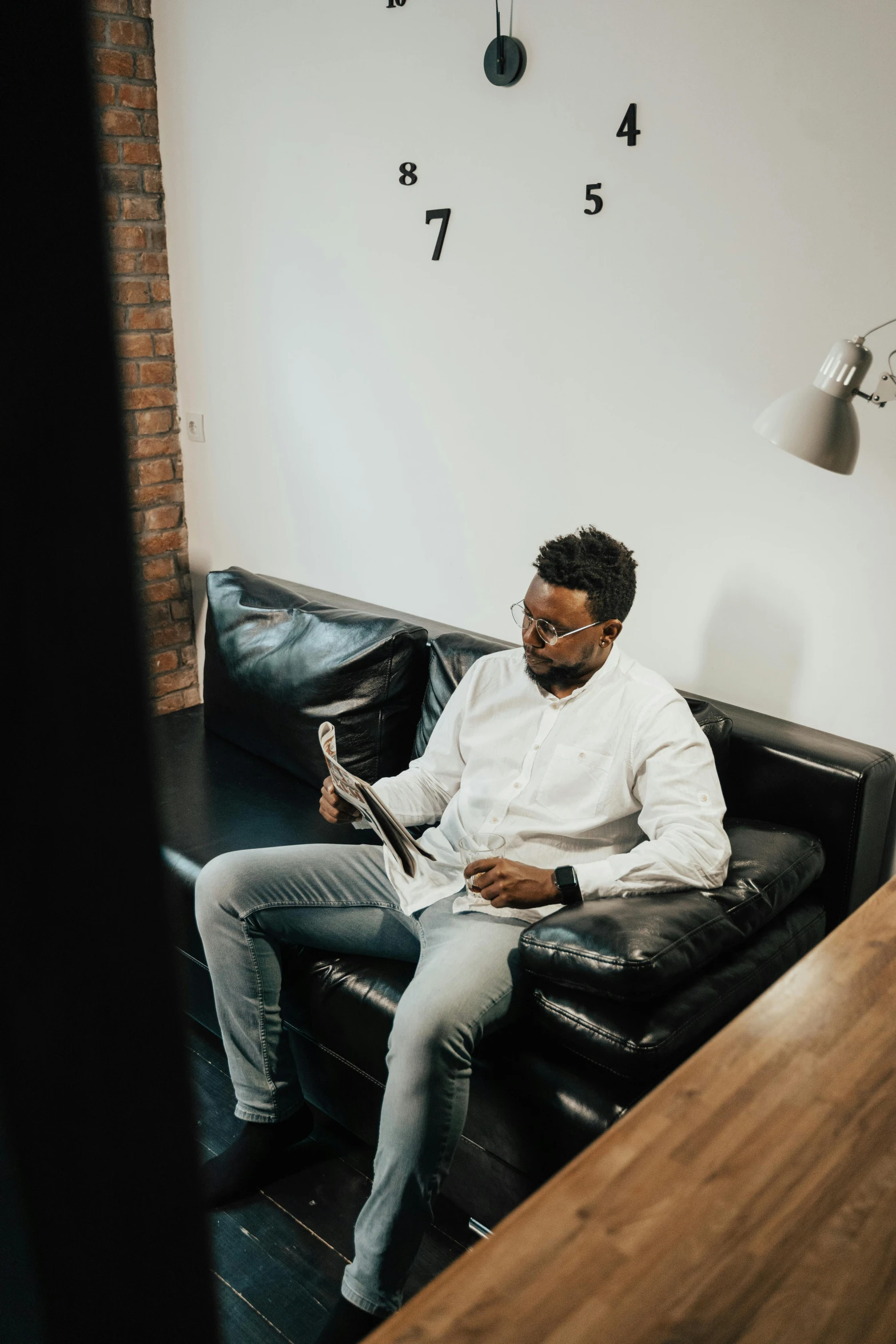 a man sitting on a couch reading a book, dark skinned, in the office, bruh moment, carson ellis