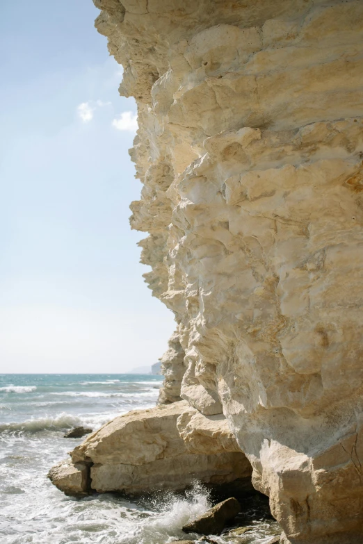 a man riding a surfboard on top of a wave covered beach, inspired by Constantine Andreou, unsplash, romanticism, white rocks made of bone, natural cave wall, low - relief stone sculpture, cyprus