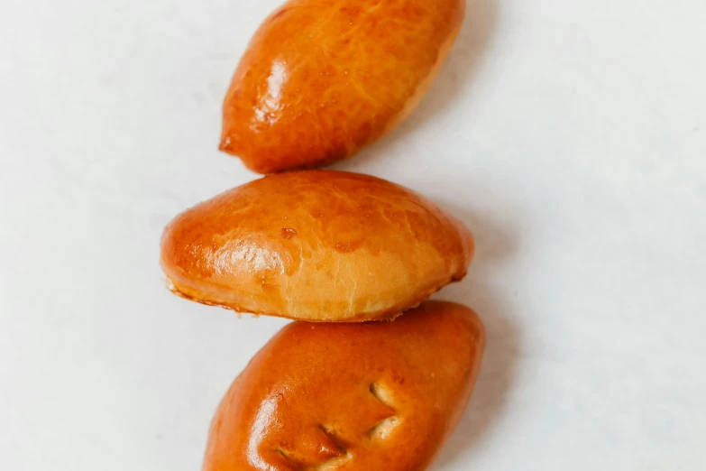 a close up of three doughnuts on a white surface, hurufiyya, smooth oval shape face, daopao, detailed product image, moroccan