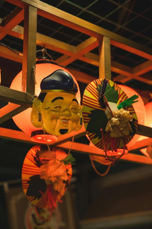 a group of asian masks hanging from a ceiling, inspired by Eiichiro Oda, mingei, street lanterns glow, closeup of the face, in a tiki bar, float