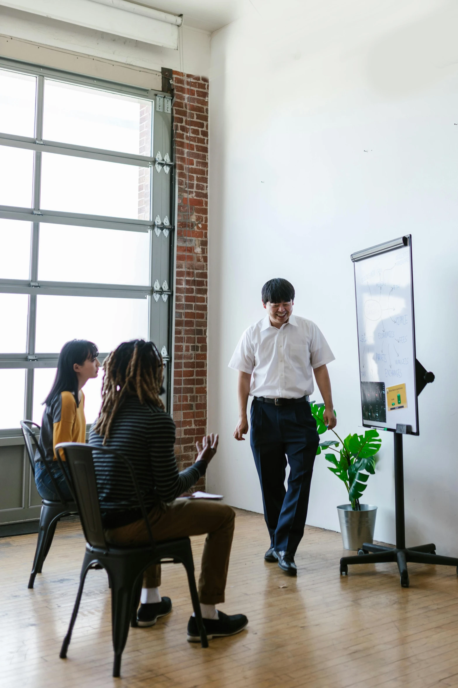 a group of people sitting around a table in a room, a picture, by Jang Seung-eop, trending on unsplash, stands at a his easel, walking to the right, whiteboard, vertical portrait