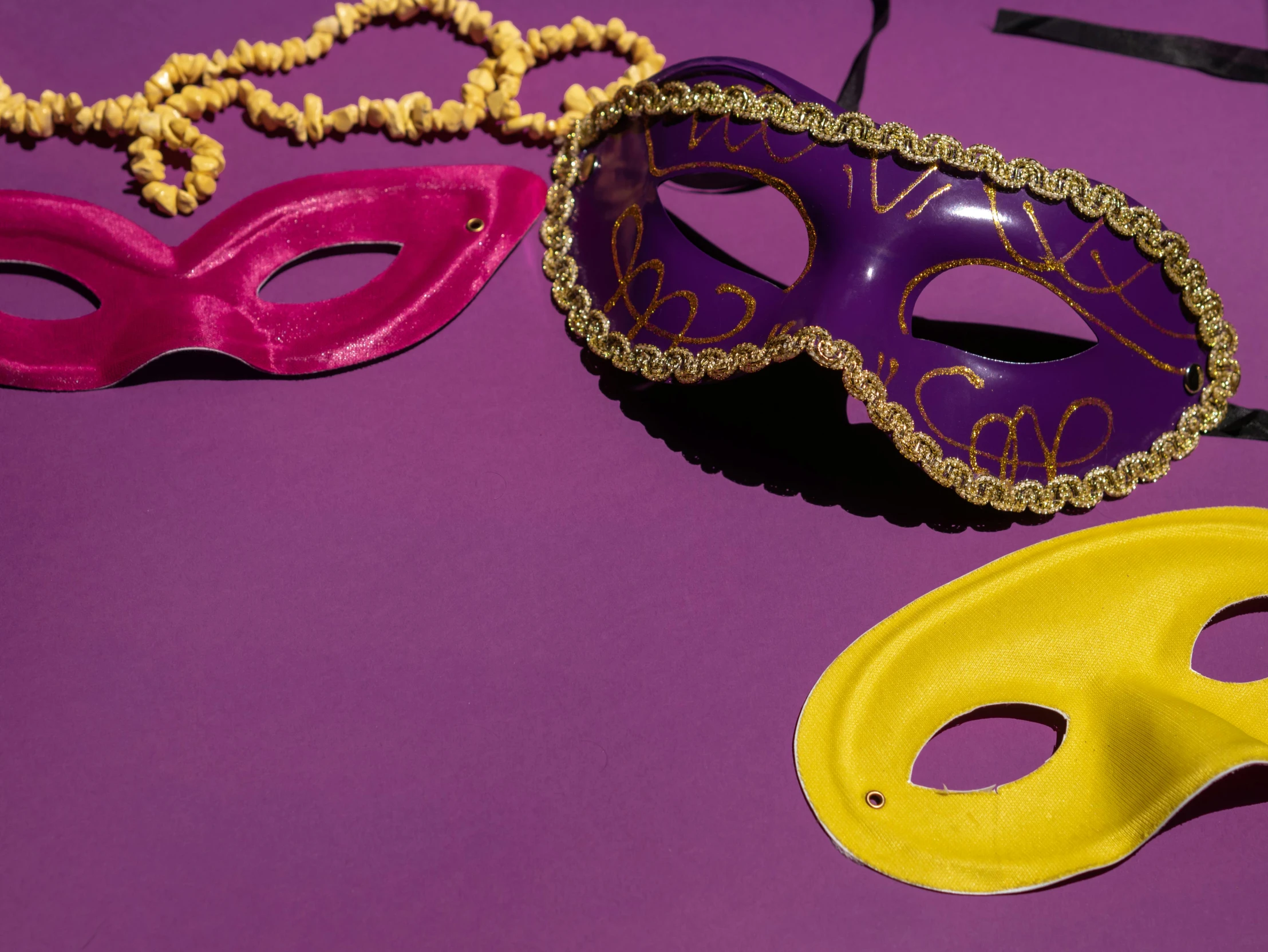 a couple of masks sitting on top of a purple table, by Carey Morris, trending on pexels, diadems, yellow purple, party, background image