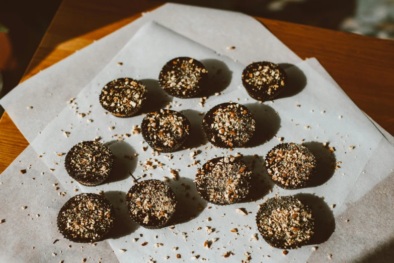 a close up of a plate of food on a table, by Daniel Lieske, unsplash, mingei, black tar particles, baking cookies, on old parchment paper, glittering