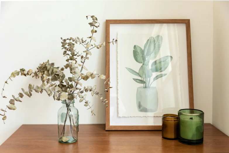 a vase filled with flowers sitting on top of a wooden table, a watercolor painting, inspired by Camille Bouvagne, visual art, sage green, wooden frame, glass jar, large leaves