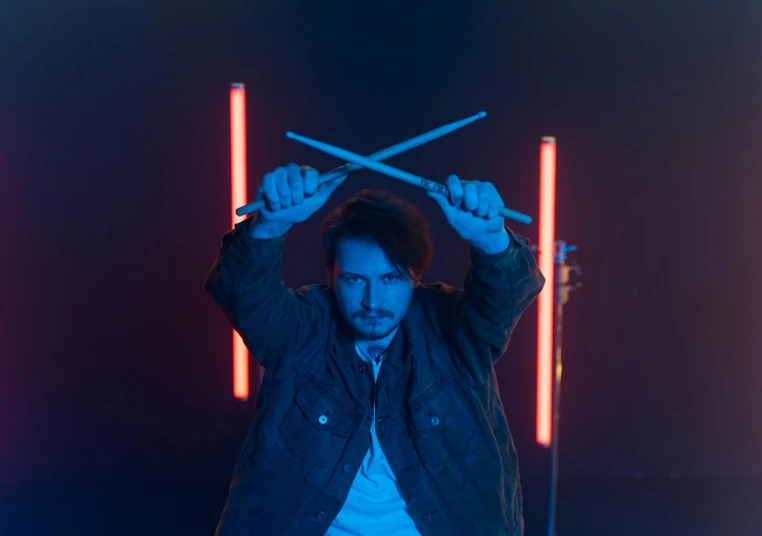 a man holding two drums in front of his head, an album cover, by Adam Marczyński, pexels contest winner, holding an activated lightsaber, mr beast, full frontal lighting, mark edward fischbach