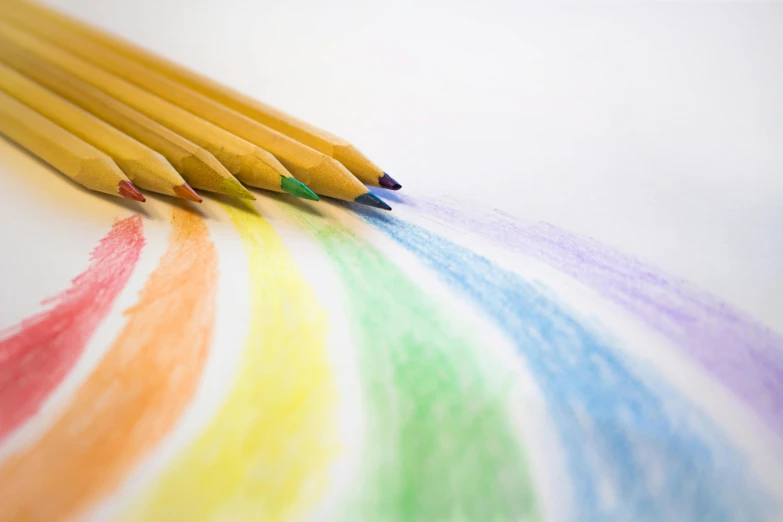 a group of colored pencils sitting on top of a table, a child's drawing, by Emma Geary, trending on pexels, lgbt flag, ethereal rainbows, drawn on white parchment paper, colored album art