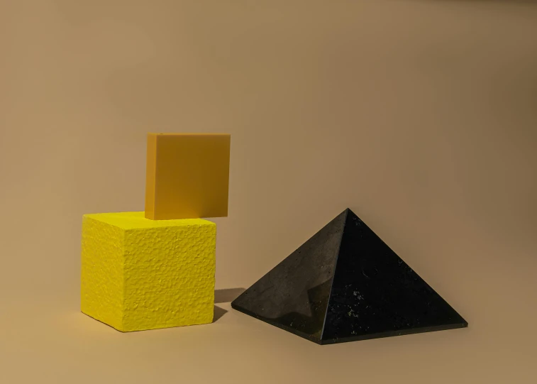 a couple of pyramids sitting next to each other, an abstract sculpture, by Harvey Quaytman, unsplash, suprematism, black. yellow, made of glowing wax and ceramic, granite, [sculpture] and [hyperrealism]