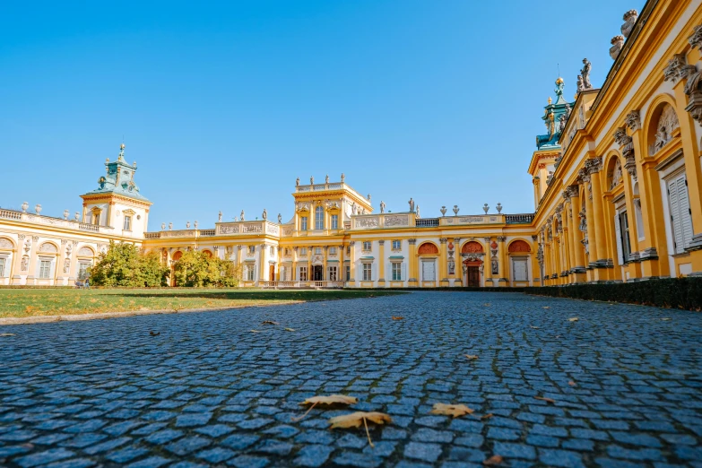 a large yellow building with a clock tower in the background, rococo, colonnade, profile image, courtyard walkway, rutkowskyi