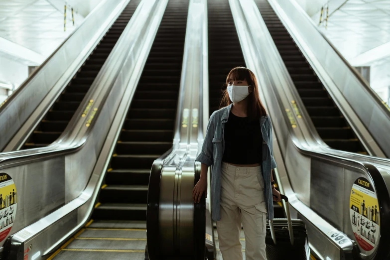 a woman wearing a face mask on an escalator, pexels contest winner, hyperrealism, luggage, avatar image, concert, 🦩🪐🐞👩🏻🦳