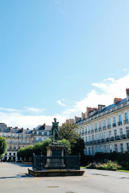 a man riding a skateboard down a street next to tall buildings, a statue, unsplash, paris school, white houses, park on a bright sunny day, square, rennes - le - chateau