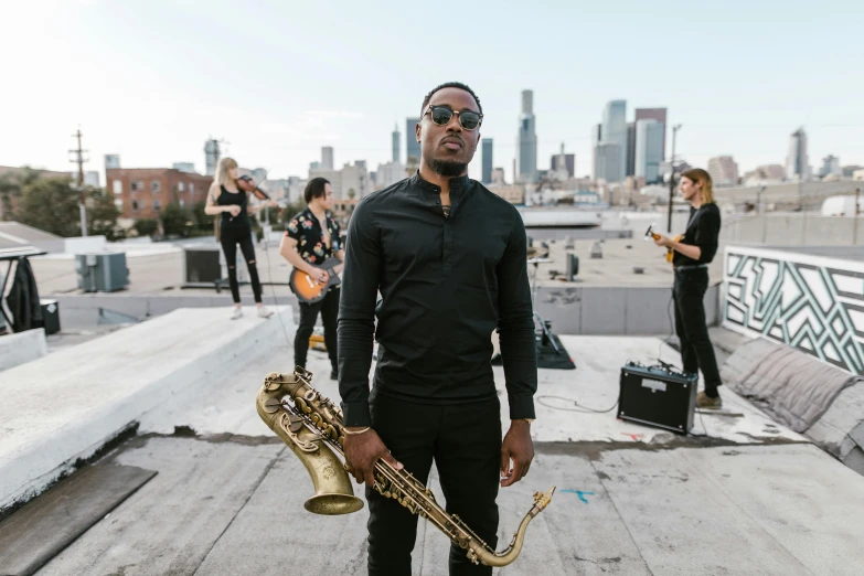 a man standing on top of a roof holding a saxophone, alexis franklin, avatar image, los angeles, group photo