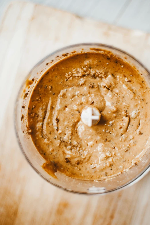 a blender sitting on top of a wooden cutting board, brown sauce, humus, detailed product image, epicurious