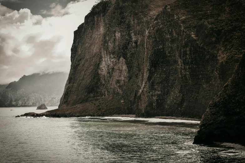 a black and white photo of a cliff and a body of water, pexels contest winner, hawaii, brown, mixed art, postprocessed