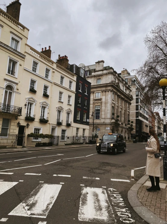 a woman standing in the middle of a crosswalk, a photo, by Maggie Hamilton, pexels contest winner, neoclassicism, some houses in the background, london, gif, square