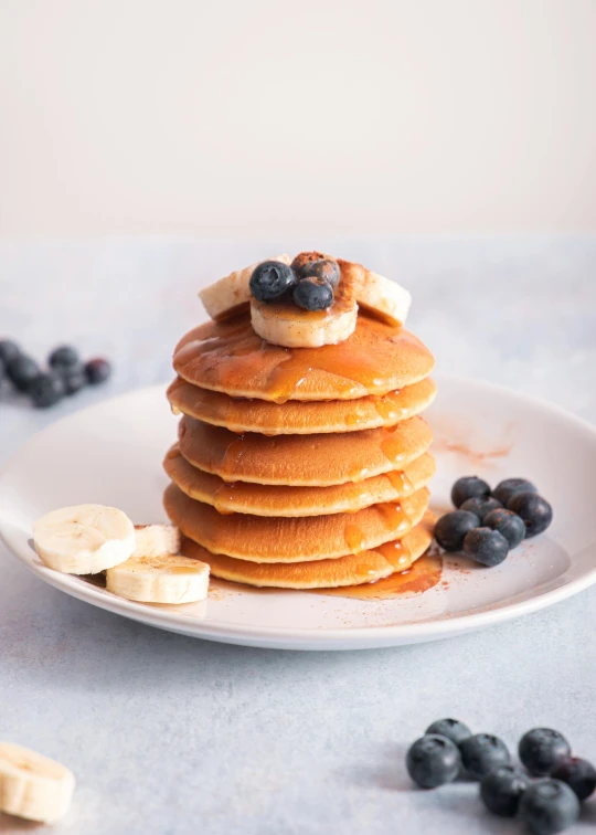 a stack of pancakes topped with bananas and blueberries, by Sam Charles, 6 pack, petite, caramel, full profile