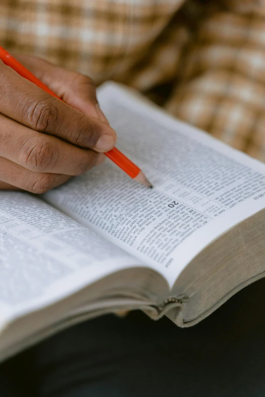 a person holding a pencil and writing in a book, bible, defined, uploaded, multiple stories