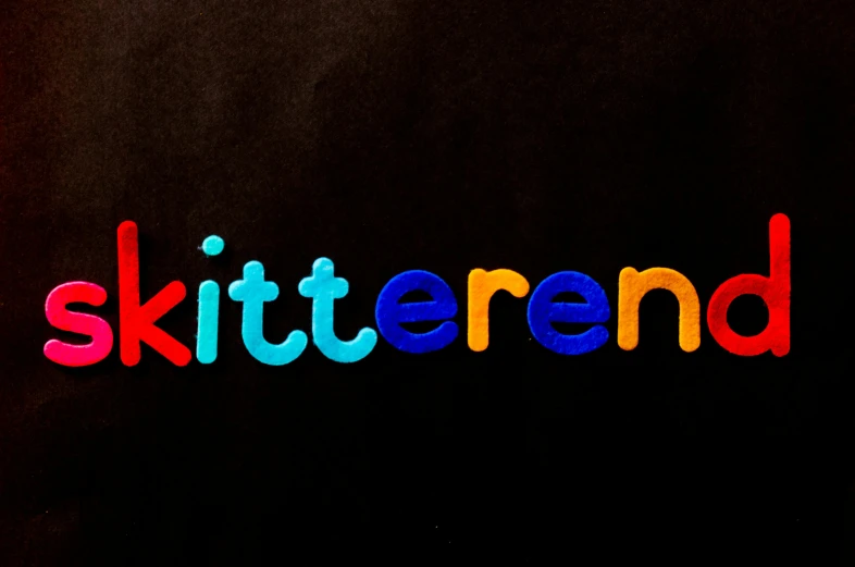 a black shirt with the word skitterrend written in multicolored letters, an album cover, by Kathleen Guthrie, shutterstock contest winner, kitsch movement, infinity symbol like a cat, y 2 k cutecore clowncore, with a black background, ( ( dithered ) )