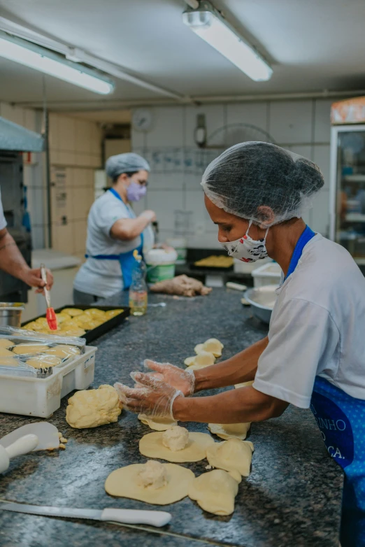 a group of people preparing food in a kitchen, in sao paulo, high-quality photo, breads, manufacturing