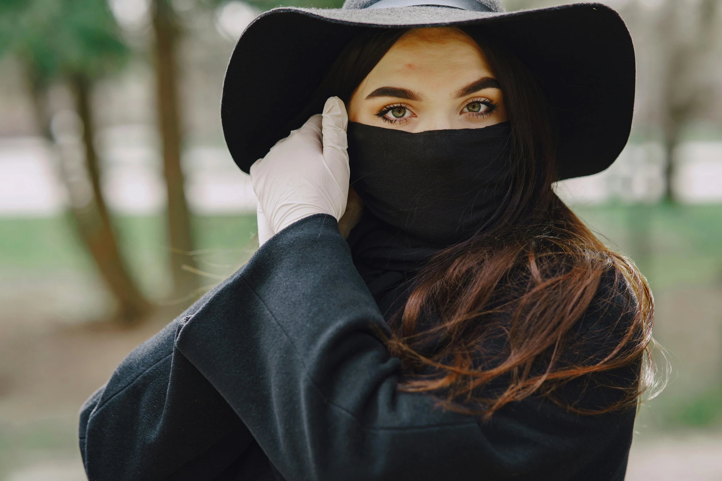 a woman wearing a black hat and a black mask, trending on pexels, renaissance, covered in robes, college, hands shielding face, handsome girl