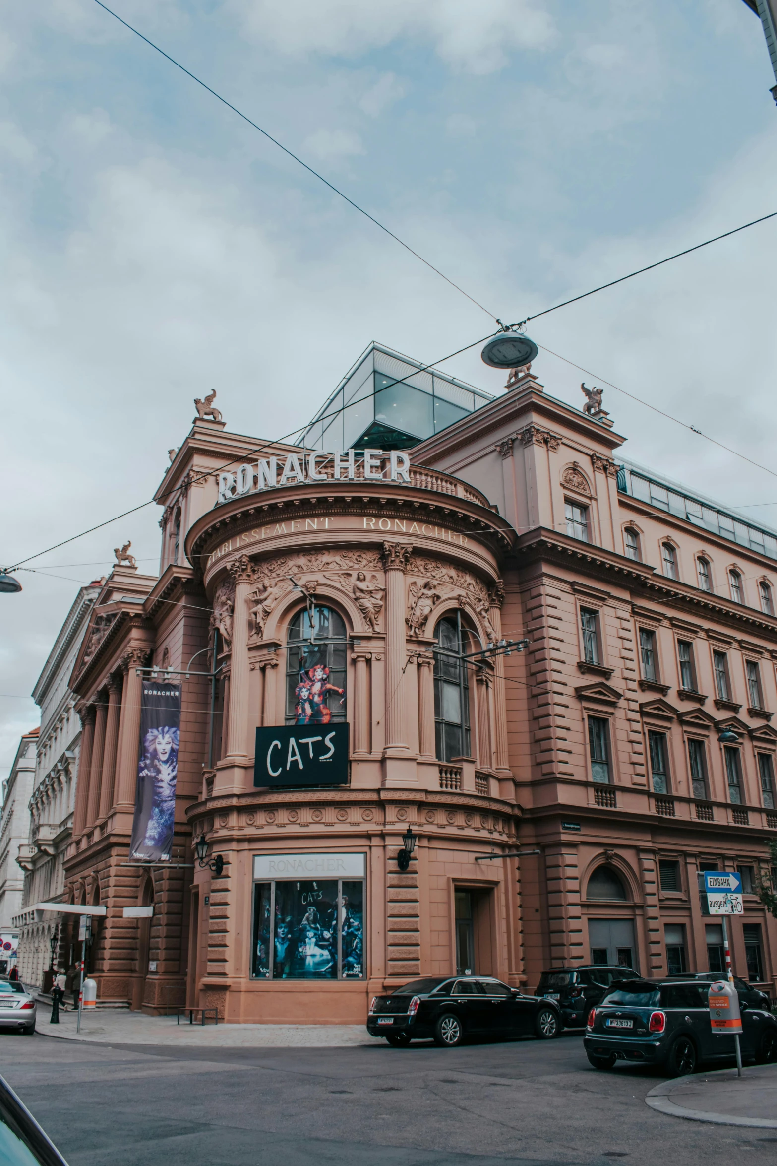 a large brown building sitting on the side of a road, viennese actionism, lots of signs and shops, cats, theatre stage, high-quality photo