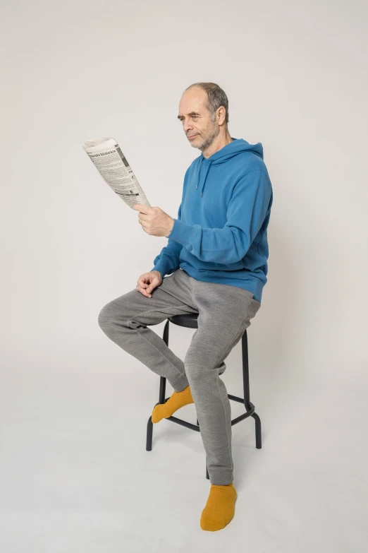 a man sitting on a stool reading a newspaper, by Will Ellis, trending on reddit, sitting dynamic pose, h3h3, grey, tim booth