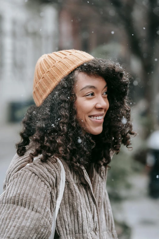 a woman walking down a street in the snow, trending on pexels, renaissance, curly middle part haircut, beanie, portrait of happy a young woman, natural skin tones