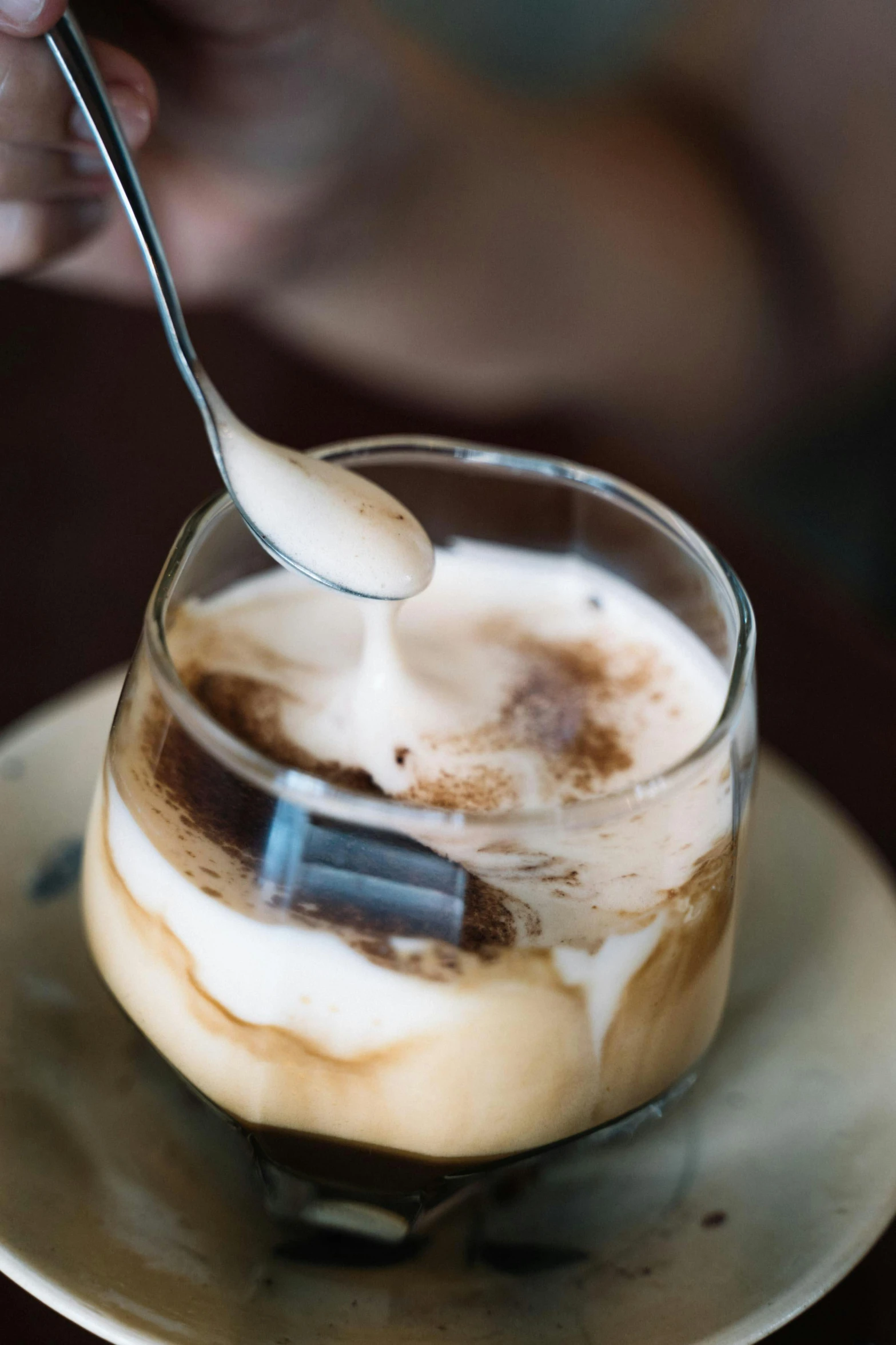 a person holding a spoon over a cup of coffee, iced latte, multiple stories, square, upclose